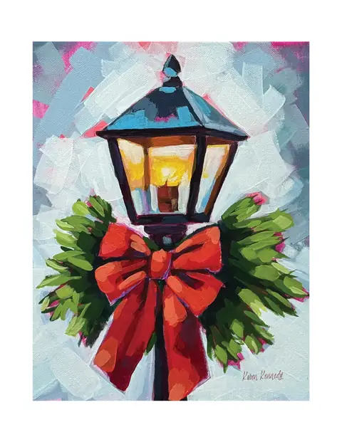 A glowing lantern decorated with greenery and a red bow.